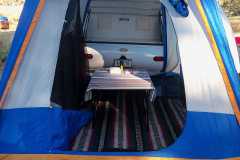 Luxurious interior of SUV tent at trailer galley hatch with wool Mexican blanket carpet.